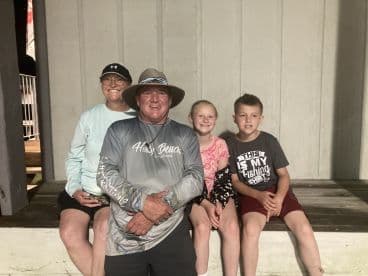 A family group poses together, showcasing their enthusiasm for fishing, with two children prominently featured.