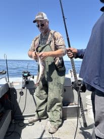 Angler actively reeling in a fish aboard a fishing boat in open water, showcasing the excitement of the catch.