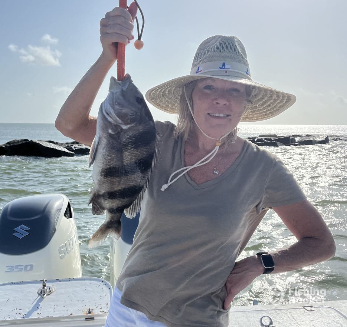 An angler proudly displaying a Sheepshead caught during a sunny day on the water, with a boat in the background.