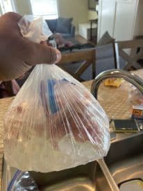 A person holding a bag of freshly caught fish on ice, ready for storage after a successful fishing trip.
