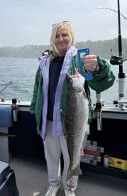 An angler proudly displaying a large Speckled Trout aboard a fishing boat, showcasing a successful day on the water.