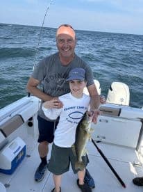 A young angler proudly displays a Walleye while fishing with a family member on a boat, enjoying a memorable day on the water.
