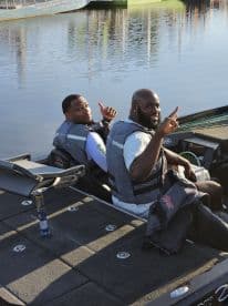 Two anglers enjoying a day on the water, seated in a well-equipped fishing boat, showcasing a friendly atmosphere.