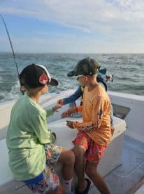 A group of young anglers engaged in conversation on the boat, enjoying a fishing trip on the open water.