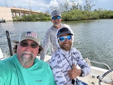 Three anglers enjoying a moment on the boat, showcasing a relaxed atmosphere before heading out for a fishing adventure.