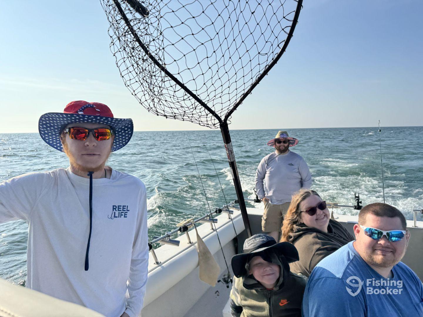 A family enjoying a day of fishing on a boat, with a young boy and adults seated comfortably as they head out to sea.