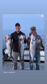 Two anglers proudly displaying their catch of Salmon while fishing on a boat, showcasing a successful day on the water.