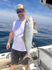 An angler proudly displaying a large fish while fishing offshore, showcasing a sunny day on the water.
