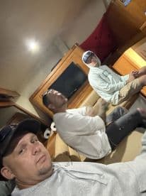 Three anglers relaxing inside the cabin of a fishing boat, showcasing comfortable seating and a cozy atmosphere.