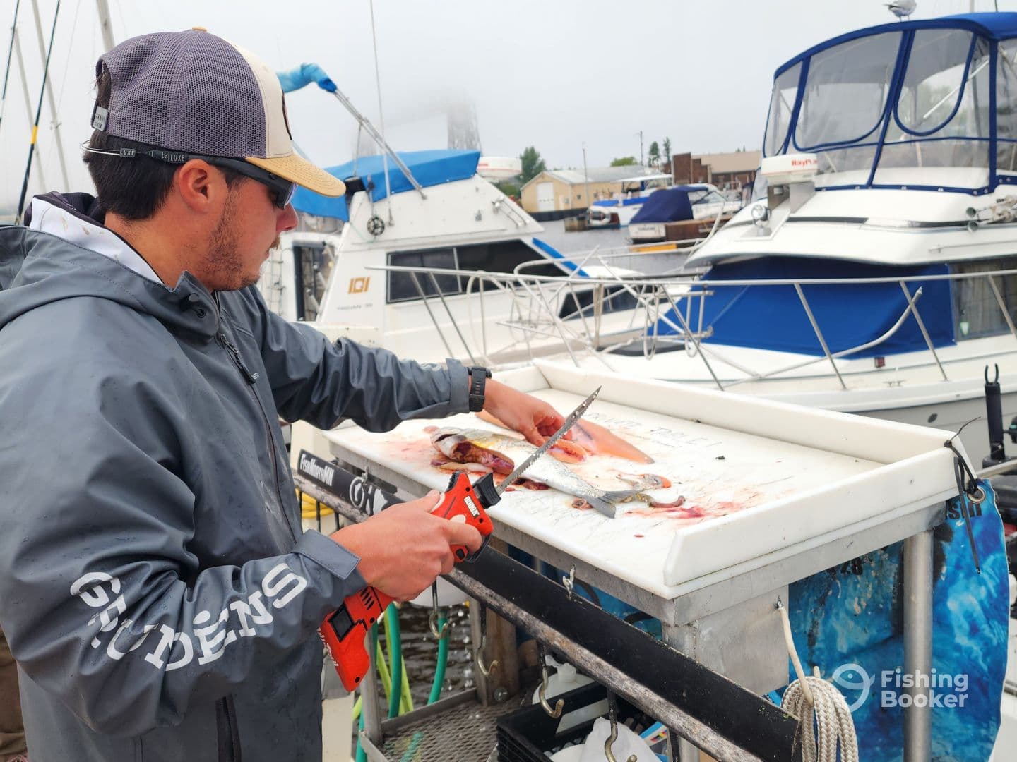 A fisherman filleting fish at a cleaning station on a dock, showcasing a variety of species after a successful fishing trip.