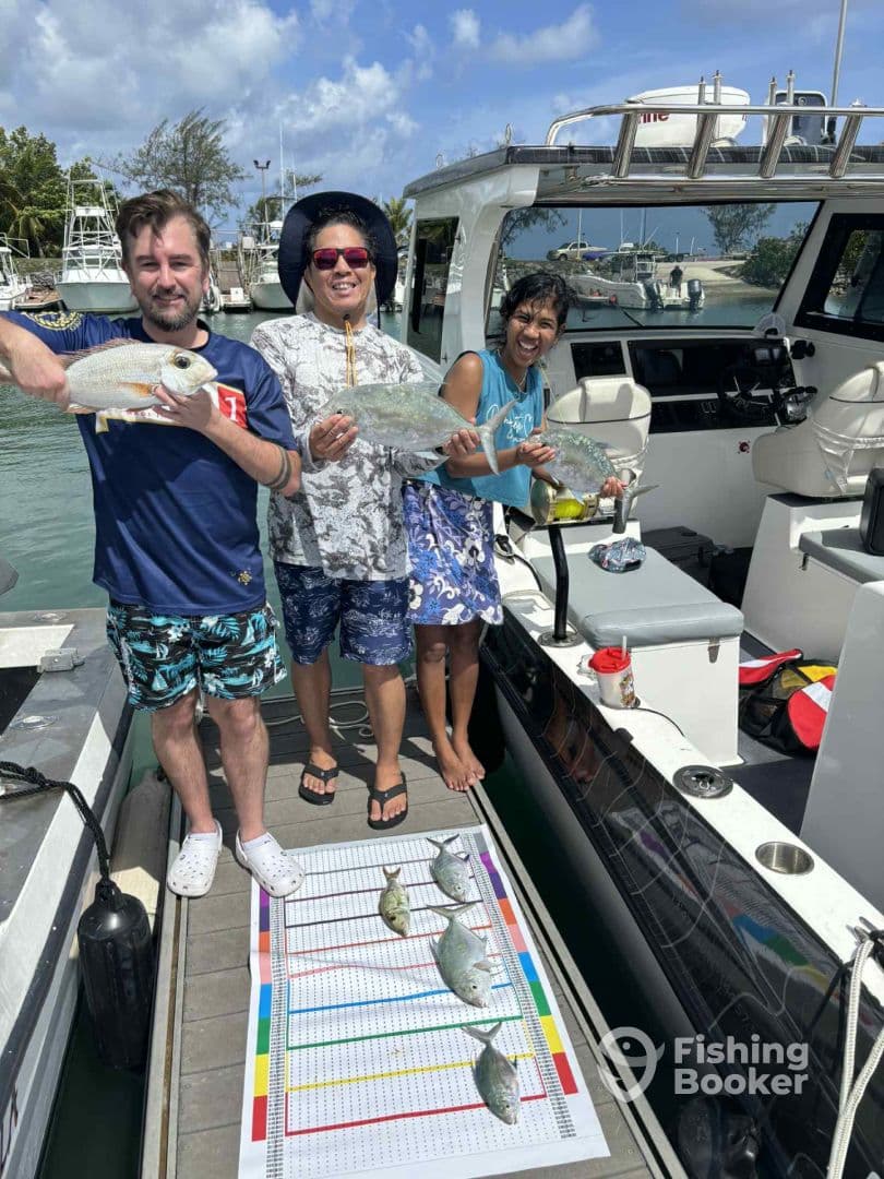 Three anglers proudly displaying their catch of various fish on a dock, with a fishing boat in the background, showcasing a fun day of fishing.