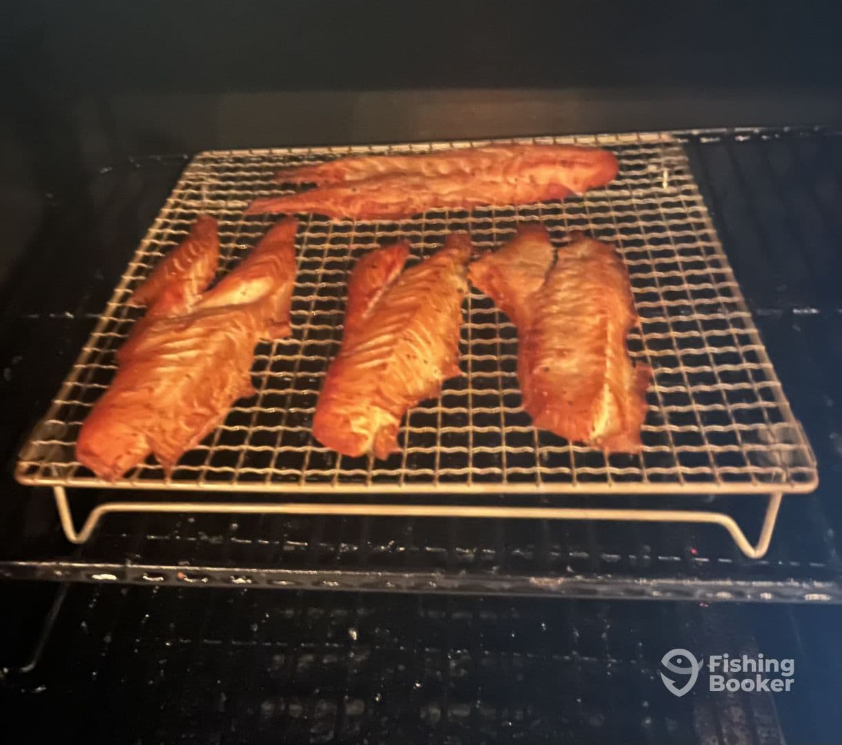 Smoked fish fillets on a rack inside a smoker, showcasing the preparation process.