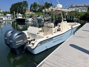 A Grady-White boat named 'Three Buoys' docked at a marina, showcasing its sleek design and twin Yamaha engines.