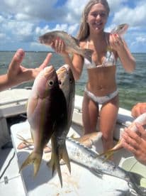 A young angler proudly displaying a variety of fish, including Snapper, while enjoying a sunny day on the water.