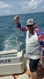 Angler proudly displaying a caught fish while aboard a fishing boat in open waters.
