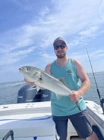 Angler proudly displaying a large Striped Bass while fishing on a boat in open waters.