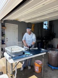 A fisherman filleting a fish at a cleaning station, showcasing the process after a successful fishing trip.