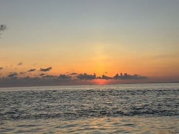 A serene sunset over the ocean, showcasing vibrant colors reflecting on the water's surface, ideal for a peaceful fishing trip.