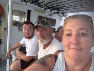 Group of anglers relaxing inside the boat, showcasing the comfortable seating and fishing gear setup.