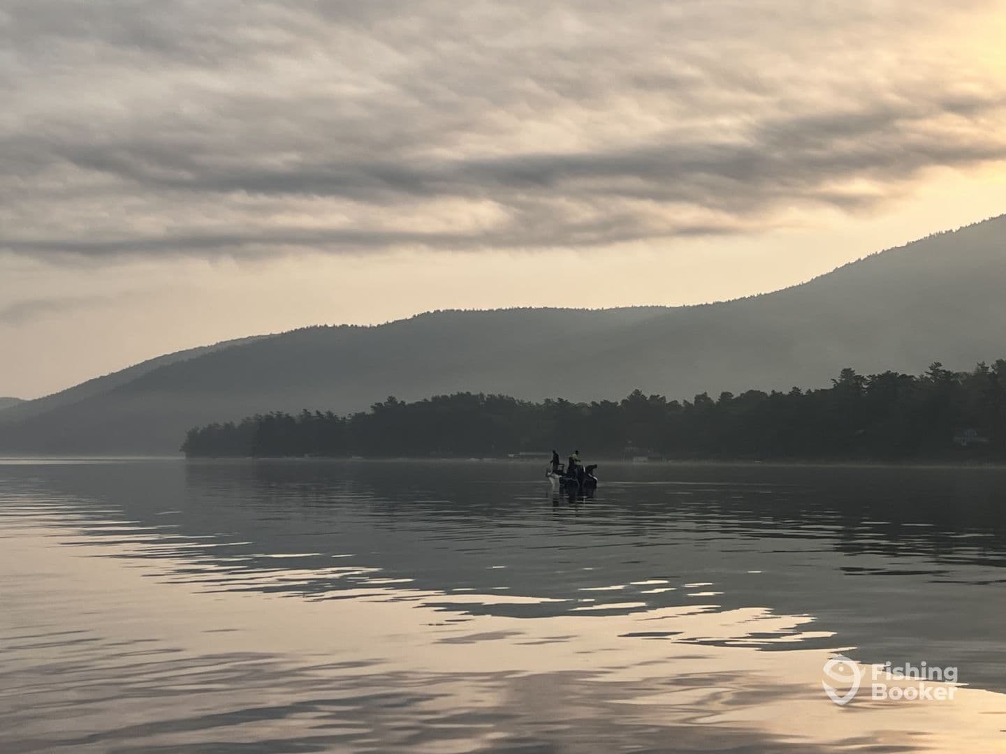 A serene morning scene featuring a fishing boat on calm waters, surrounded by misty mountains, perfect for a tranquil fishing experience.