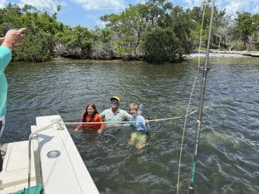 Family enjoying a fun day on the water, with kids playing in the shallow area near the boat.