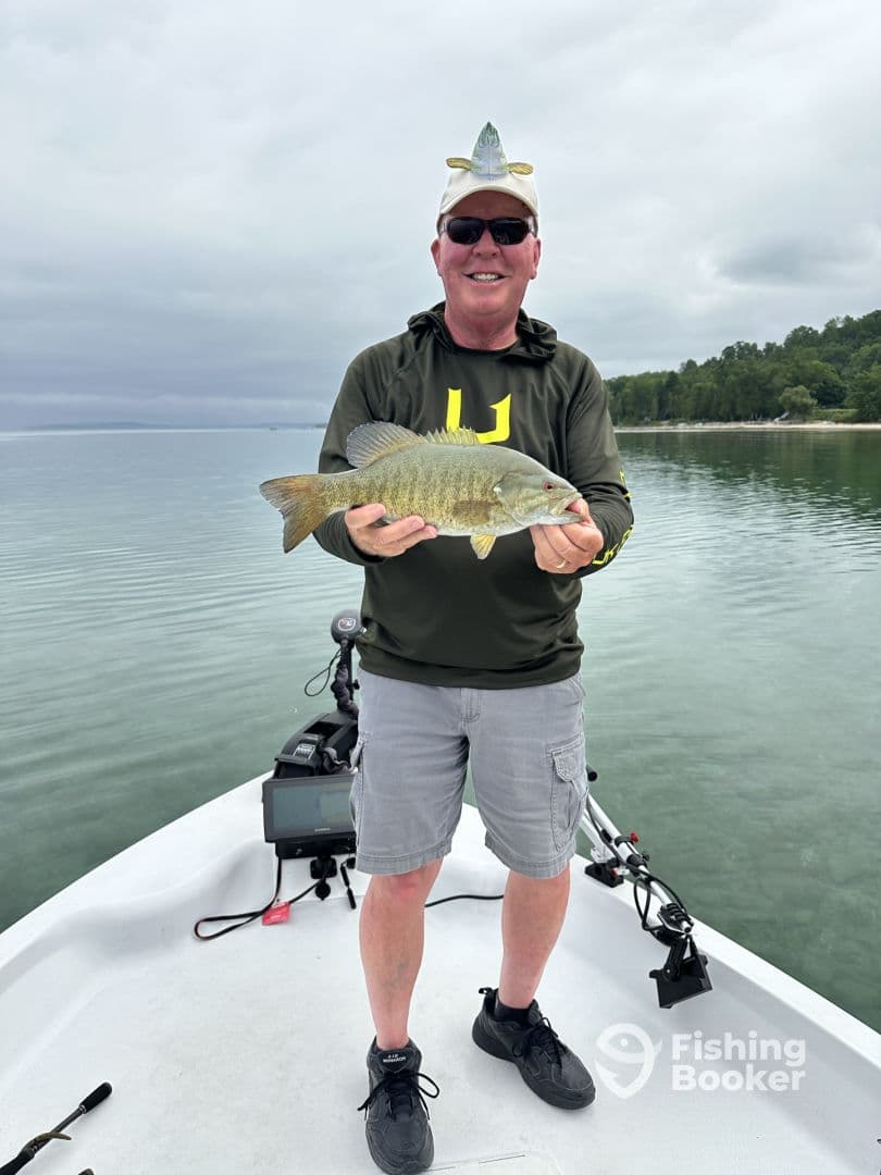 An angler proudly displaying a Smallmouth Bass while fishing on a calm lake, showcasing a fun and relaxed fishing experience.