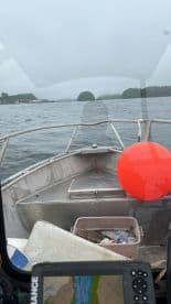 View from the helm of a fishing boat, showcasing the interior layout and navigation equipment while on a calm waterway.