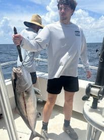 A young angler proudly displaying a large fish on a fishing boat, showcasing a successful day on the water.
