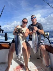 Two anglers proudly displaying their catch of Yellowfin Tuna aboard a sportfishing boat in open waters.