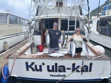 Two anglers proudly displaying their catch of multiple Mahi Mahi aboard the Ku'ula-kai after a successful fishing trip in Nawiliwili.
