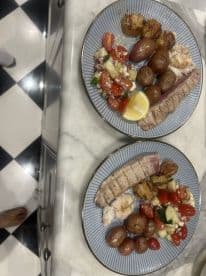 Plates of grilled fish and sides presented on a marble countertop, showcasing a meal rather than a fishing catch.