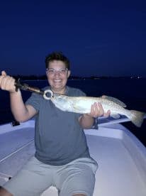 Young angler proudly displaying a Speckled Trout caught during a night fishing trip.