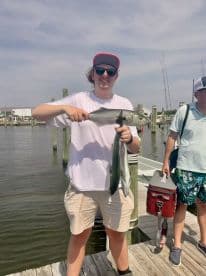 An angler proudly displaying a large fish while standing on the dock, showcasing a successful fishing trip.