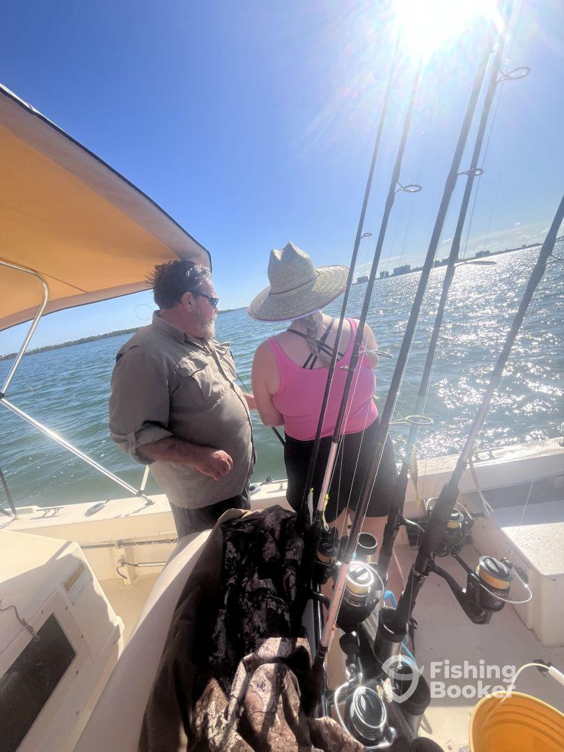 Two anglers enjoying a day on the water, discussing fishing techniques aboard a well-equipped boat with multiple fishing rods visible.