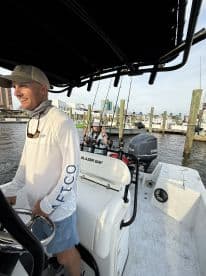 The captain navigates a Blazer Bay boat with fishing gear ready, showcasing a lively fishing atmosphere in a bustling marina.