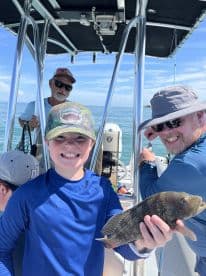 A young angler proudly displaying a caught fish while enjoying a day on the water with family.