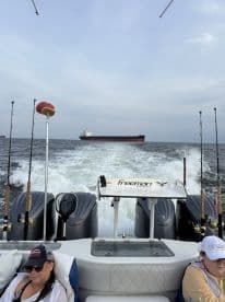 Interior view of a Freeman boat with two anglers relaxing in the seating area while cruising on the open water, showcasing the boat's design and fishing readiness.