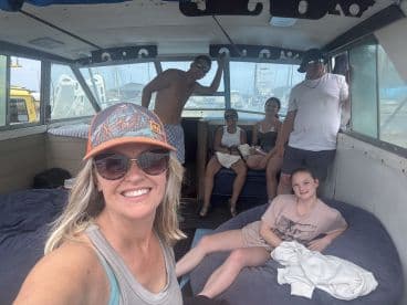 A group of six enjoying the interior of a fishing boat, showcasing comfortable seating and a relaxed atmosphere before heading out on a fishing adventure.