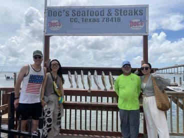 A group of anglers proudly posing with their catch of Speckled Trout displayed on a board at Doc's Seafood & Steaks in Texas.