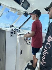 A young boy confidently steering the boat from the helm, showcasing the interior of a fishing vessel.