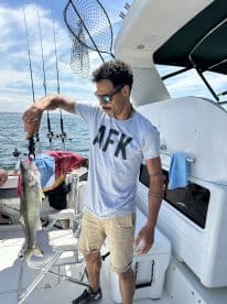 An angler proudly displaying a large Walleye while fishing on a boat, showcasing a sunny day on the water.