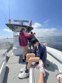 A group of young anglers enjoying a day on the water, with a view of the boat's interior and fishing equipment.