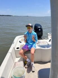 A young angler enjoying a sunny day on a boat, showcasing a relaxed atmosphere with fishing gear visible.