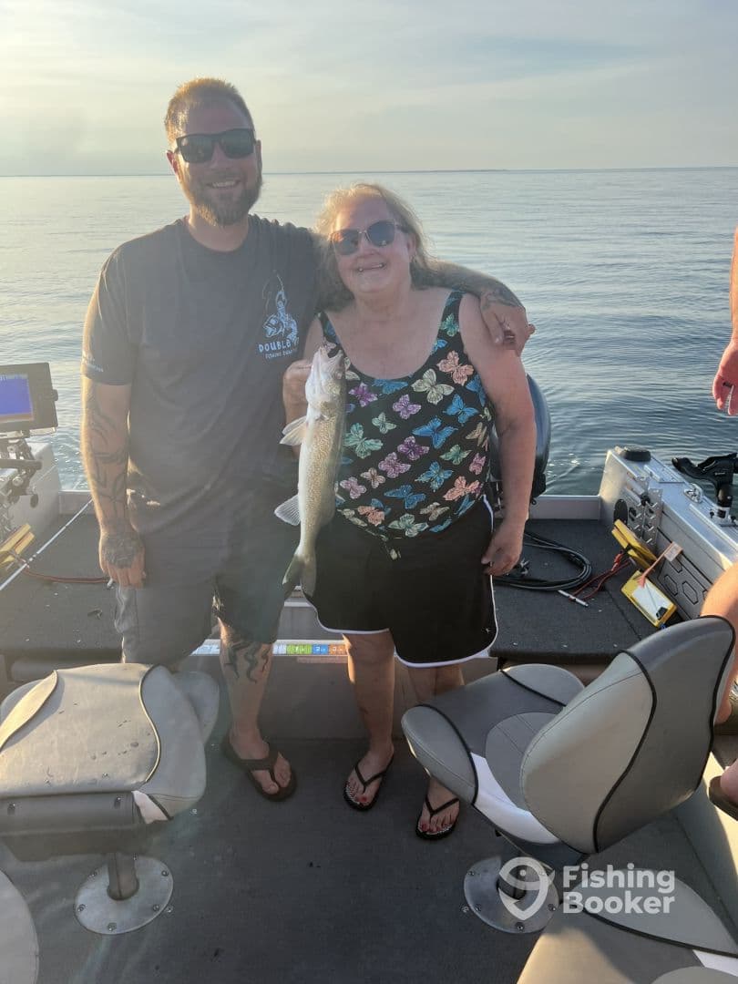 Two anglers proudly displaying a caught fish on a boat during a serene fishing trip.