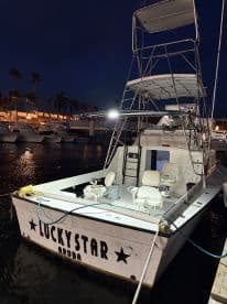 The exterior of the 'Lucky Star' fishing boat docked at night in Aruba, showcasing its seating and fishing amenities.
