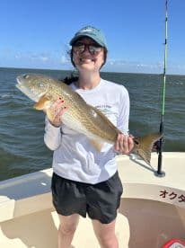 Angler proudly displaying a large Redfish while fishing on a sunny day, showcasing the excitement of a successful catch.