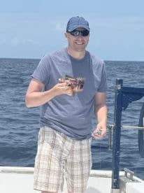 An angler proudly displaying a freshly caught fish while fishing offshore, showcasing a sunny day on the water.