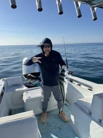 Angler displaying a large fish while aboard a boat in calm waters, showcasing a successful fishing trip.