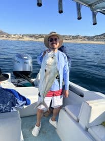 An angler proudly displaying a large fish while aboard a boat, enjoying a sunny day on the water.