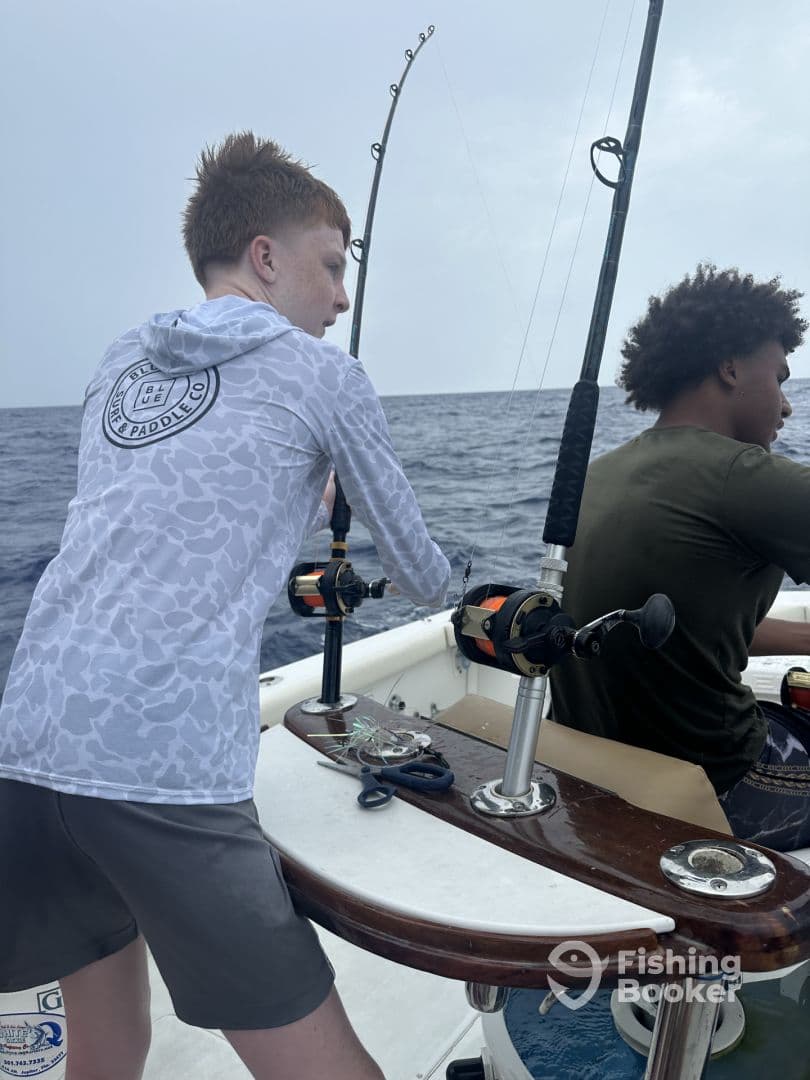 Two young anglers engaged in fishing on a boat, with rods in hand, showcasing the excitement of deep-sea fishing.